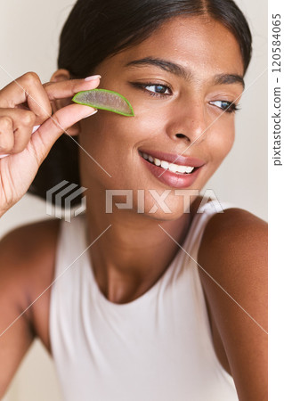 Radiant Woman Smiling While Applying Fresh Aloe Vera on Her Skin 120584065