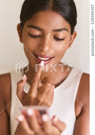 Woman Applying Lip Gloss Smiling While Looking at Mirror Reflecting Confidence Woman Applying Lip Gloss Smiling While Looking at Mirror Reflecting Confidence 120584107