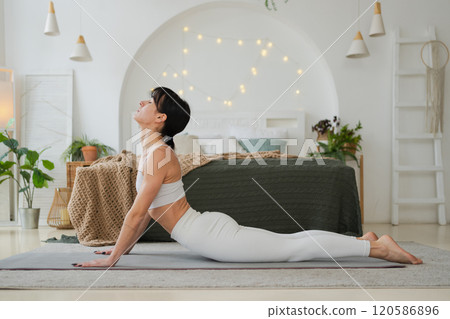 Yoga fitness workout training. Woman practicing yoga at home. Woman doing sports exercise on yoga mat on floor indoor. Girl in sportswear have training workout for weight loss. Sport and fitness 120586896