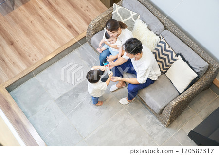 Four parents and children relaxing on a sofa in a room 120587317
