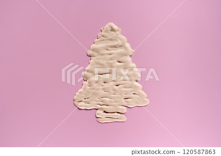 beige cream shaped like a Christmas tree on pink background. Holiday foundation makeup and body care 120587863