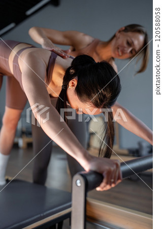 Woman training pilates on the reformer bed with trainer. Reformer pilates studio machine for fitness workouts in gym. Fit, healthy and strong authentical body. Fitness concept Woman training pilates on the reformer bed with trainer. Reformer pilates studio machine for fitness workouts in gym. Fit, healthy and strong authentical body. Fitness concept 120588058