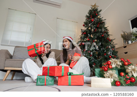 Joyful Young Couple Celebrating Christmas at Home with Gifts and Festive Decorations 120588160
