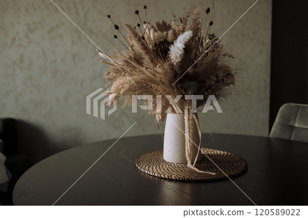 Stylish modern dried flower arrangement in a cream vase at home room. Composition with many different dried flowers in vases, on a light background. 120589022