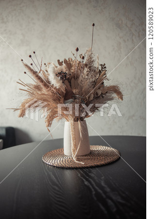 Stylish modern dried flower arrangement in a cream vase at home room. Composition with many different dried flowers in vases, on a light background. 120589023