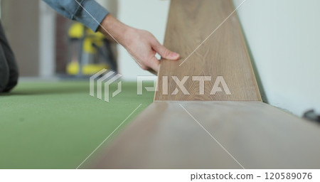Worker, lays laminate on a green backing. Technology and process. Repair of the floor of the house. Worker, lays laminate on a green backing. Technology and process. Repair of the floor of the house. 120589076