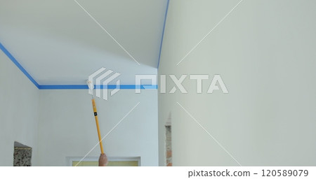 Painting the ceiling with a long stick with a roller. Home repairs and finishing works. Painting the ceiling with a long stick with a roller. Home repairs and finishing works. 120589079