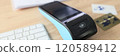 Portable terminal and bank credit cards lie on wooden table 120589412