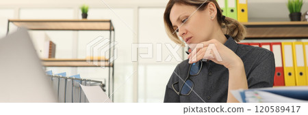 Woman worker holds glasses reading investigation document Woman worker holds glasses reading investigation document 120589417