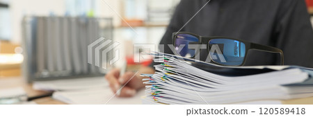 Glasses put on stack of folders with working documents Glasses put on stack of folders with working documents 120589418