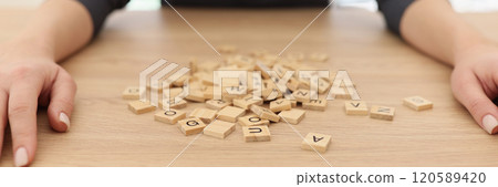 Woman puts hands on sides of wooden cubes pile lying on table 120589420