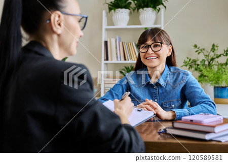 Middle aged positive woman patient on therapy meeting with professional mental therapist 120589581