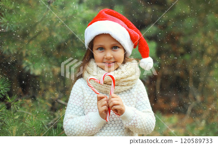 Christmas portrait of happy smiling little girl child in santa red hat with sweet lollipop cane toys 120589733