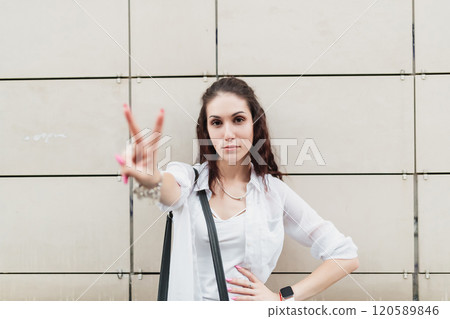 Young woman shows peace sign in urban setting during daytime Young woman shows peace sign in urban setting during daytime 120589846