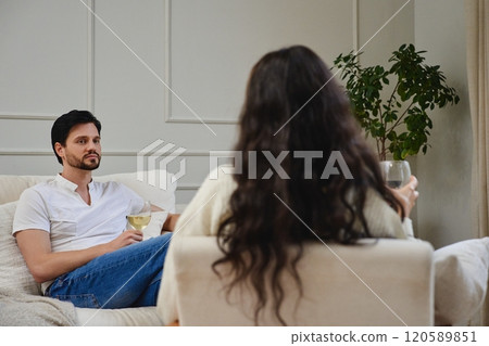 Couple enjoying drinks and conversation in a cozy living room setting 120589851