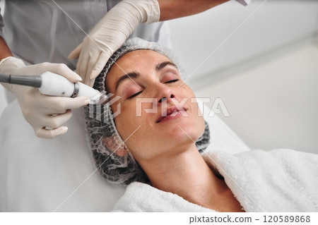 Woman receiving a facial treatment at a skincare clinic in a serene setting 120589868