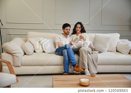Cozy couple reading together in a modern living room setting Cozy couple reading together in a modern living room setting 120589883
