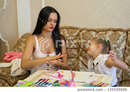 Mother and daughter enjoying craft activities together in a cozy living room 120589896