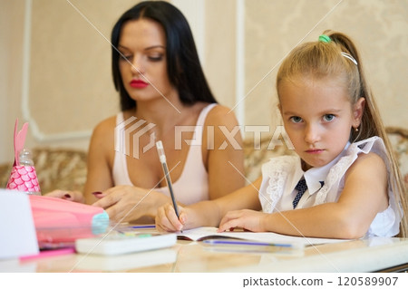 Mother and daughter engaged in homework together at a stylish home setting Mother and daughter engaged in homework together at a stylish home setting 120589907
