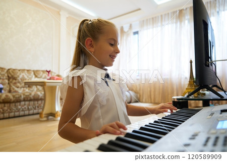 Young girl enjoying music while playing keyboard in a bright living room Young girl enjoying music while playing keyboard in a bright living room 120589909