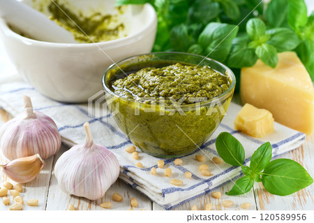 Traditional italian sauce pesto in a bowl with basil leaves on a light kitchen table table. 120589956