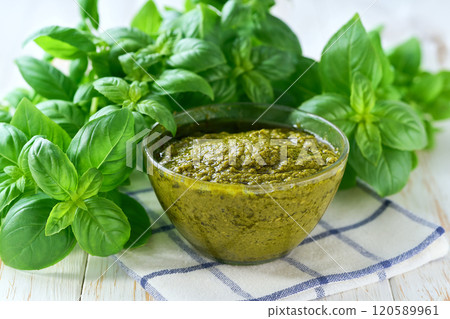 Bowl of tasty pesto sauce with basil leaves on a white table. 120589961