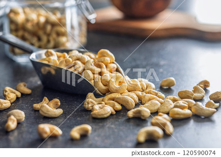 Roasted cashew nuts in scoop on black table. Roasted cashew nuts in scoop on black table. 120590074