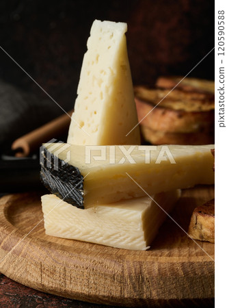 Triangular pieces of cheese and fried ciabatta slices on a wooden board 120590588