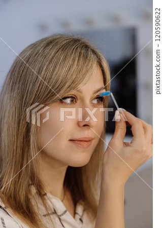 Close up of eyebrow grooming with blue spoolie brush for flawless beauty and defined brows 120590622