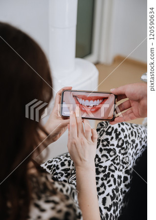 Patient reviewing smile transformation on smartphone at dental clinic consultation Patient reviewing smile transformation on smartphone at dental clinic consultation 120590634