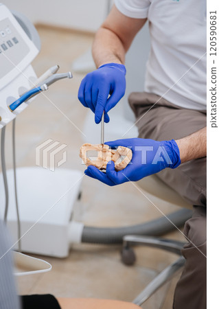 Dentist demonstrating dental model procedure with precision tools in a modern clinic setting Dentist demonstrating dental model procedure with precision tools in a modern clinic setting 120590681