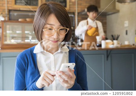 一位女士在咖啡館操作智慧型手機 120591802