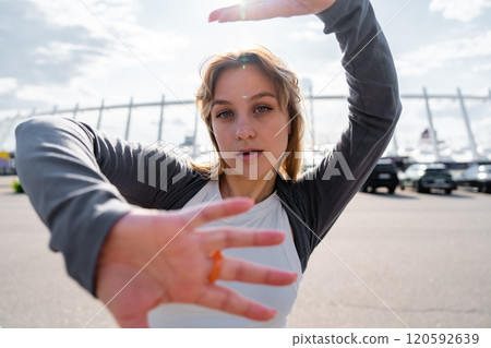 Young woman dancing outdoors with expressive hand movements in bright daylight Young woman dancing outdoors with expressive hand movements in bright daylight 120592639