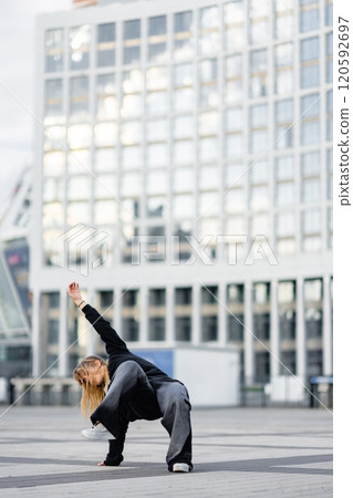 Dancer performing dynamic move in urban setting during evening light Dancer performing dynamic move in urban setting during evening light 120592697