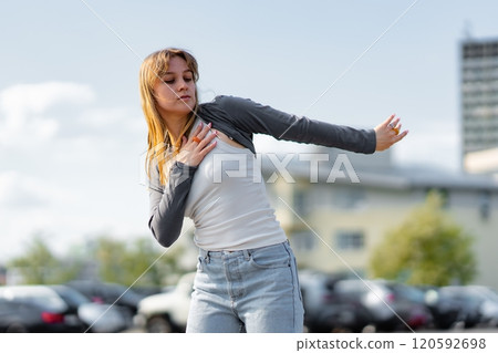 Young woman dancing joyfully in an urban parking lot under clear sky Young woman dancing joyfully in an urban parking lot under clear sky 120592698