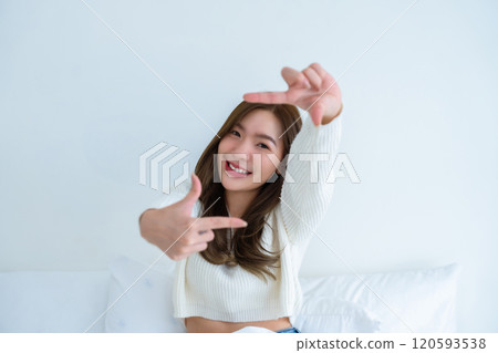 Young asian woman happy and making frame with fingers on white background in house Young asian woman happy and making frame with fingers on white background in house 120593538