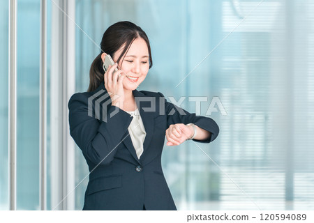 Smiling young Asian businesswoman talking on her smartphone 120594089