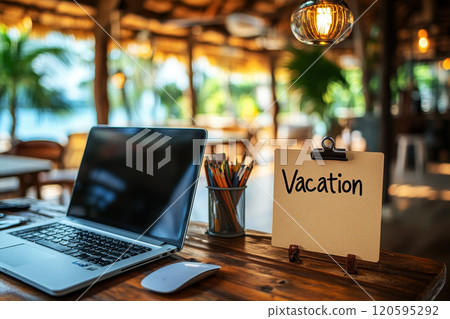 Office table with the message: Vacation or holidays written on a note. Laptop and office supplies on blurred background. Out of the office. 120595292