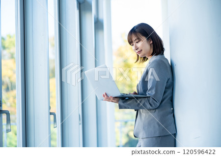 一位穿著西裝的女士正在使用電腦檢查數據。 120596422
