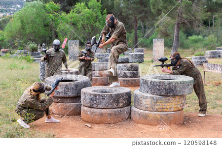 Two active opposing teams with guns playing paintball 120598148