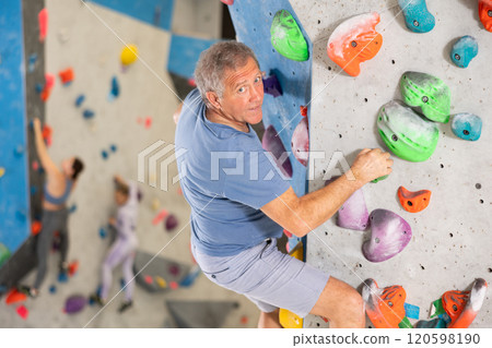 Male mountaineer climbing artificial rock wall without belay indoors Male mountaineer climbing artificial rock wall without belay indoors 120598190
