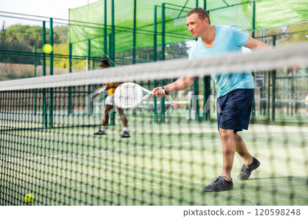 Concentrated man padel player hitting ball with racket Concentrated man padel player hitting ball with racket 120598248