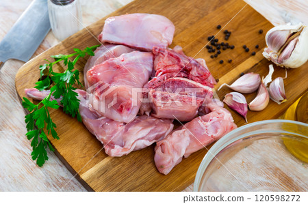 Raw sliced rabbit lying on wooden cutting board with seasonings 120598272