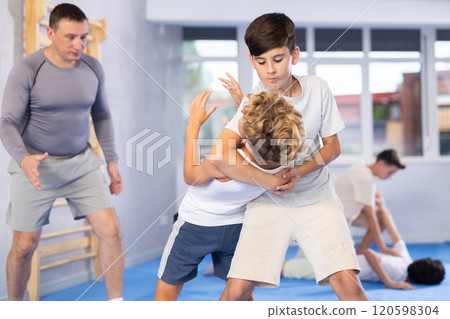 Teenagers practicing inverted facelock self-defense technique in training bout 120598304