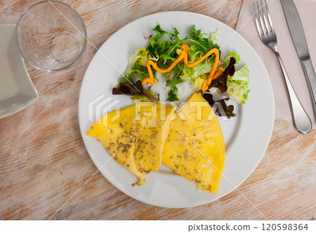 Fried omelette with herbs and fresh green salad 120598364