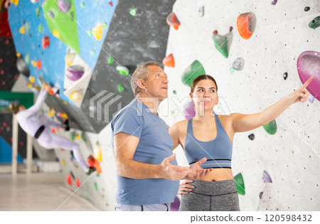 Interested young girl and elderly man talking near bouldering wall 120598432