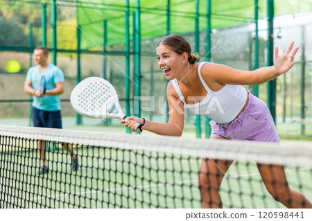 Young woman padel tennis player trains on the outdoor court 120598441