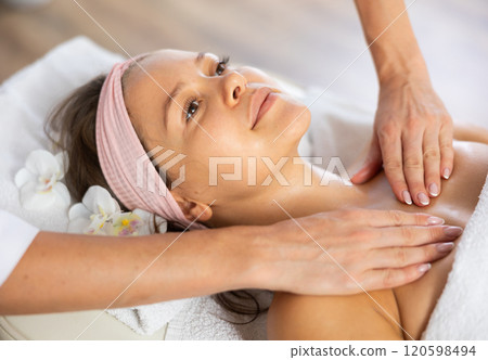 Young woman client gets procedure of rejuvenating decollete and neck massage 120598494