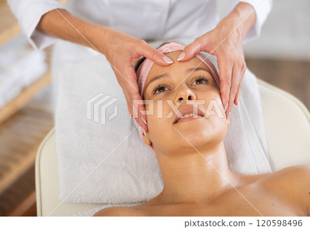 Young woman client gets procedure of rejuvenating massage face skin on cosmetologist visit 120598496