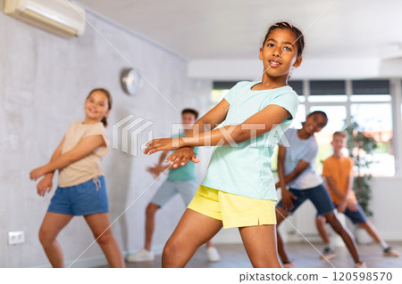 Energetic african american tween girl practicing vigorous dance in group class 120598570